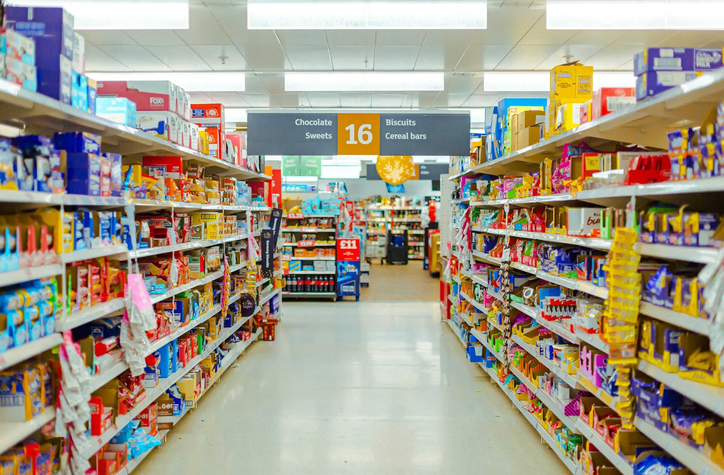 Supermarket aisle with chocolate, sweets, biscuits and cereal bars on the shelves.